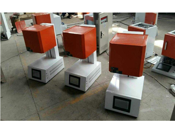 Vertical lift furnace units with elevated heating enclosures and individual front control screens in a workshop