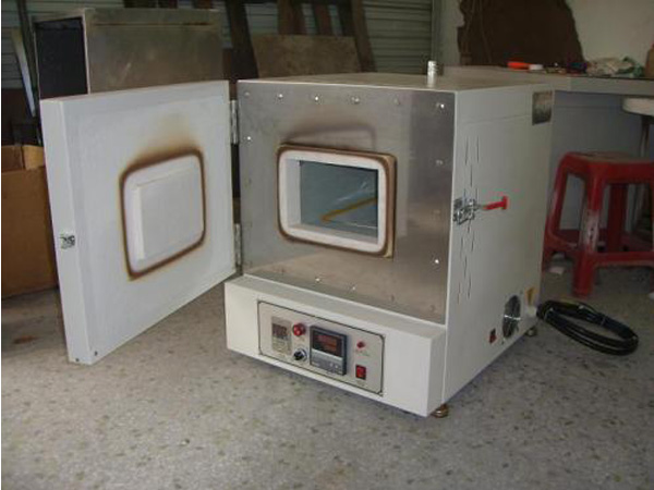 Muffle furnace with open insulated door, rectangular sample chamber and integrated lower control panel